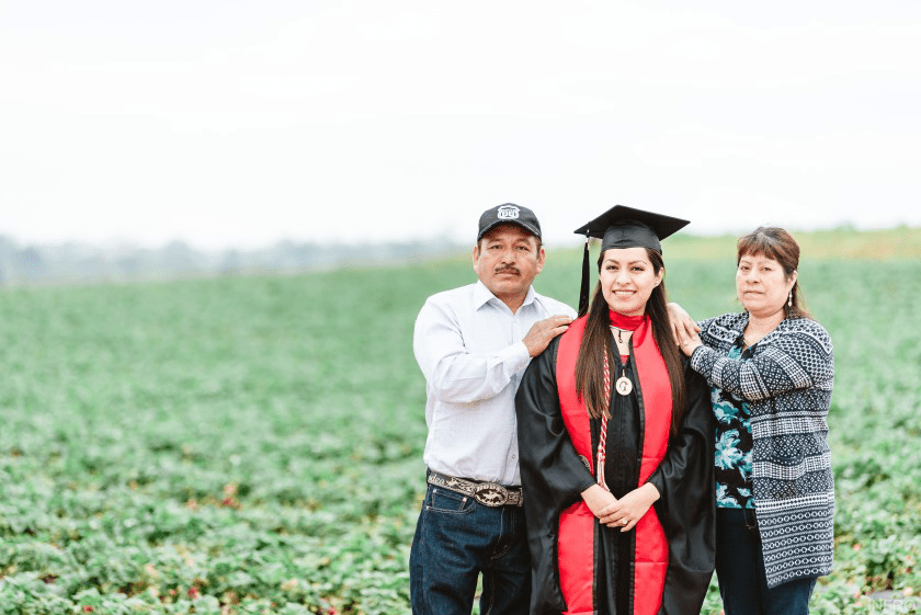 A UH graduate photographed in a field with her family.