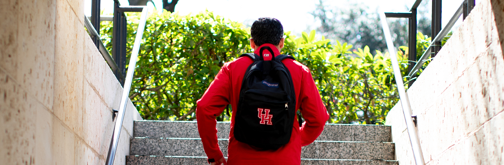 Student with UH backpack walking up stairs