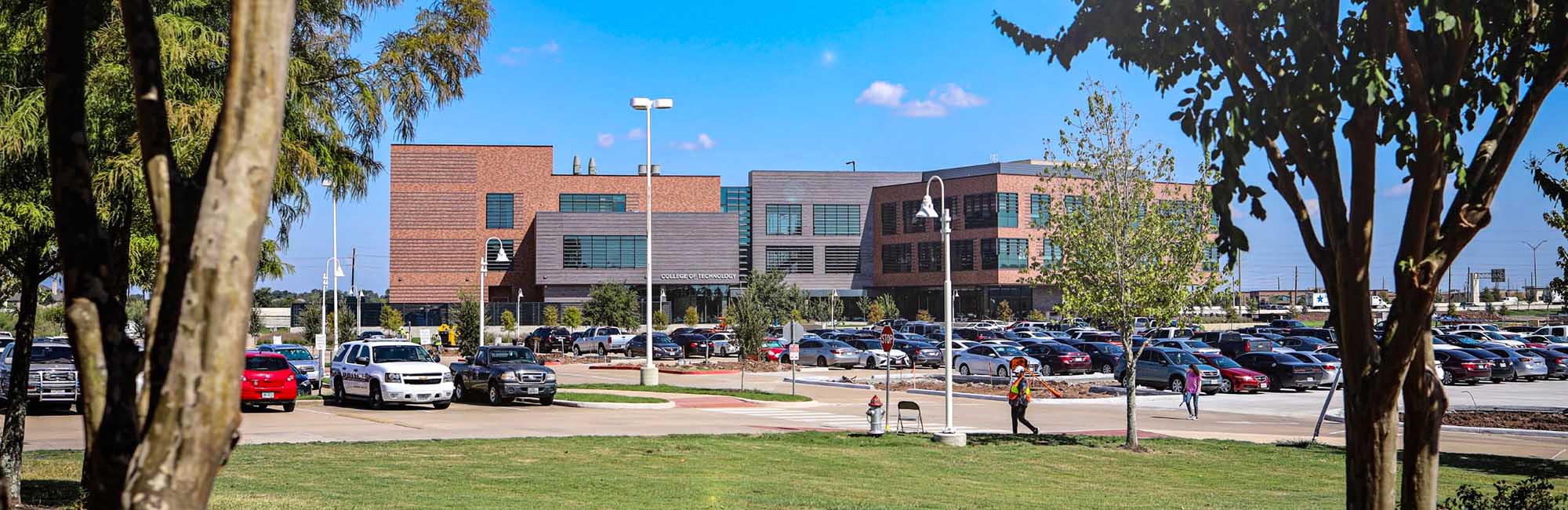 A gray and brown building with a parking lot in front of it.