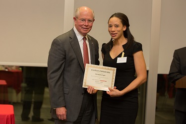 A man in suit giving a certificate to a woman in a black dress