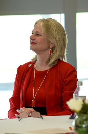 A blonde woman wearing a red suit sitting at a table