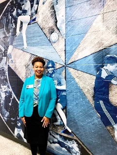 A woman with short brown standing in front of blue sports wall mural