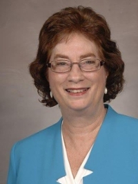 Portrait of a red-headed woman in glasses wearing a blue suit