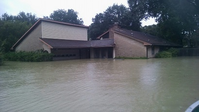 A flooded brown brick house with water rising to the windows