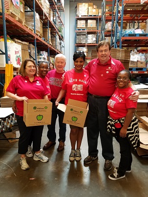 A group of faculty and students holding boxes in a warehouse