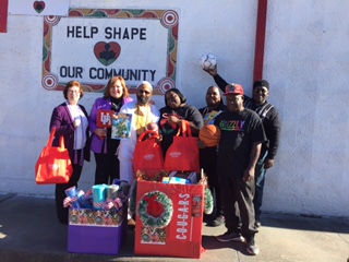 A group of people with bags and boxes of gifts standing outside a community center