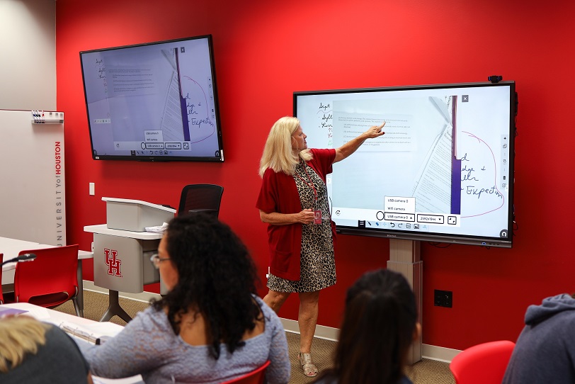 An instructor pointing to notes displayed on a large monitor.