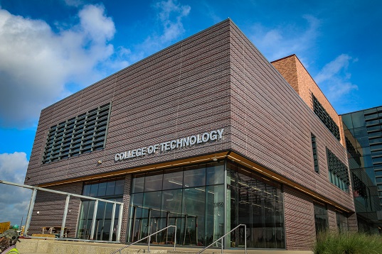 The corner of a dark brown building with the words 'College of Technology' on the side