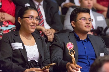 A hispanic woman and man sitting in an audience