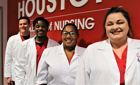 A diverse group of nursing students wearing lab coats and red scrubs