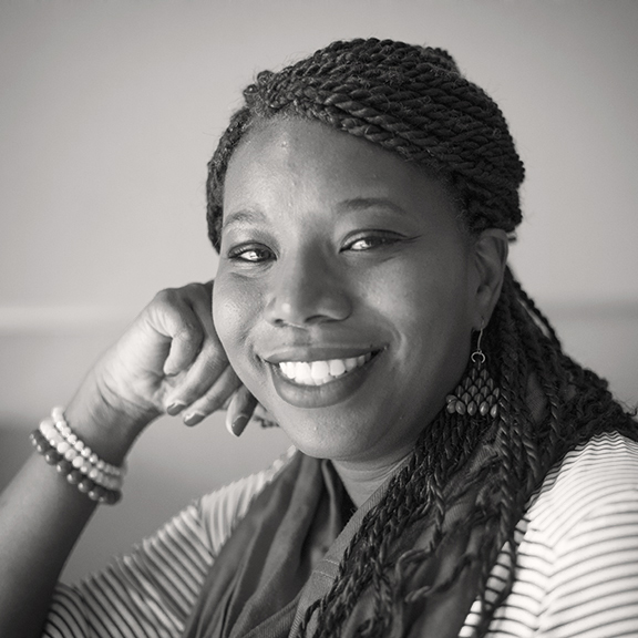 Black and white portrait of a Black woman with braided hair smiling.