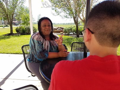 An African-American woman sitting at an outdoor table with a male student