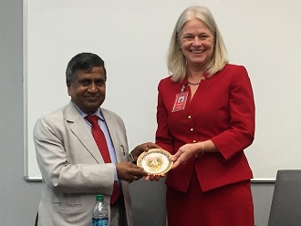 A man in a light grey suit holding a piece of art with a woman in a red suit