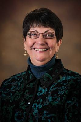 Portrait of a smiling woman with short dark-brown hair wearing glasses