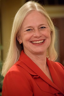 Portrait of a blond woman wearing a red suit smiling