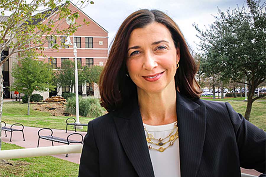 Portrait of a hispanic woman with brown hair wearing dark business jacket.