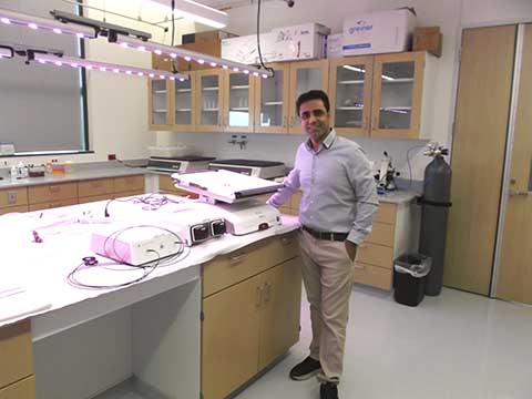  Picture of a professor smiling next to donated equipment.