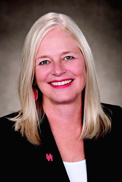 Portrait of a blonde woman smiling wearing a black business jacket with a small red UH lapel pin.