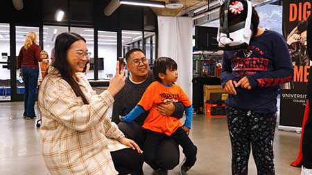 A child uses a virtual reality headset while her parents and sibling watch.