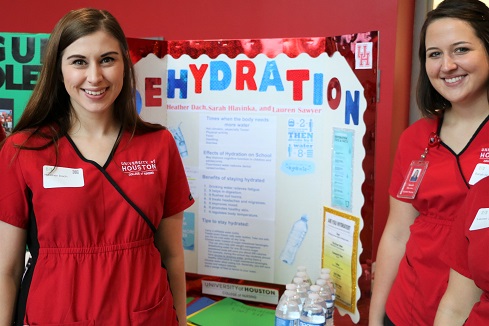Two female nursing students stand by a research poster about dehydration