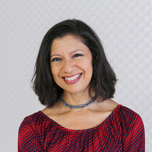 Portrait of a Hispanic woman smiling with dark shoulder length hair wearing a necklace and a red blouse
