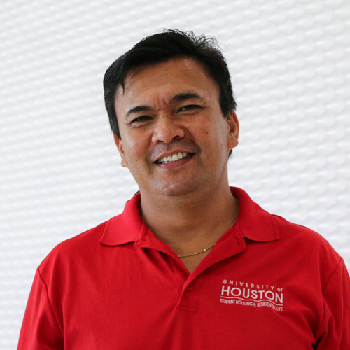 Portrait of a Hispanic man smiling wearing a blue button-up shirt