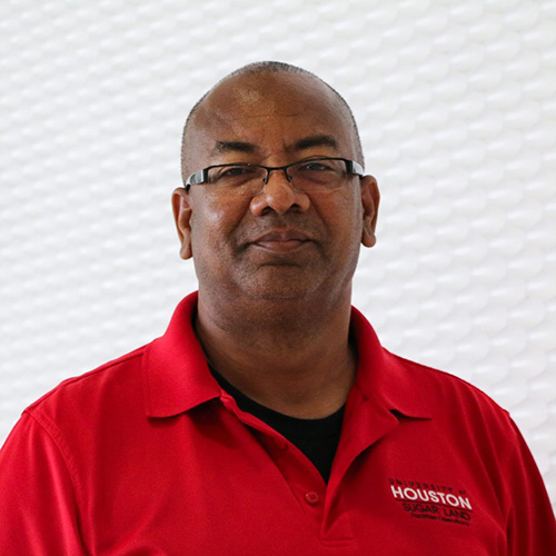 Portrait of a bald black man wearing glasses and a red polo shirt