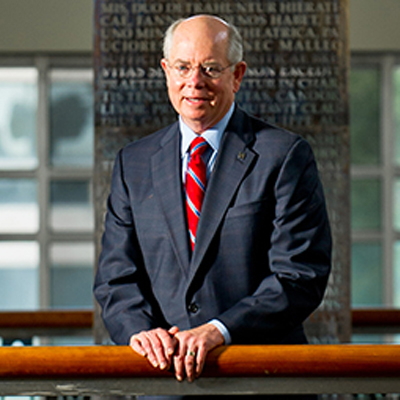 A man in a suit standing in front of a rail