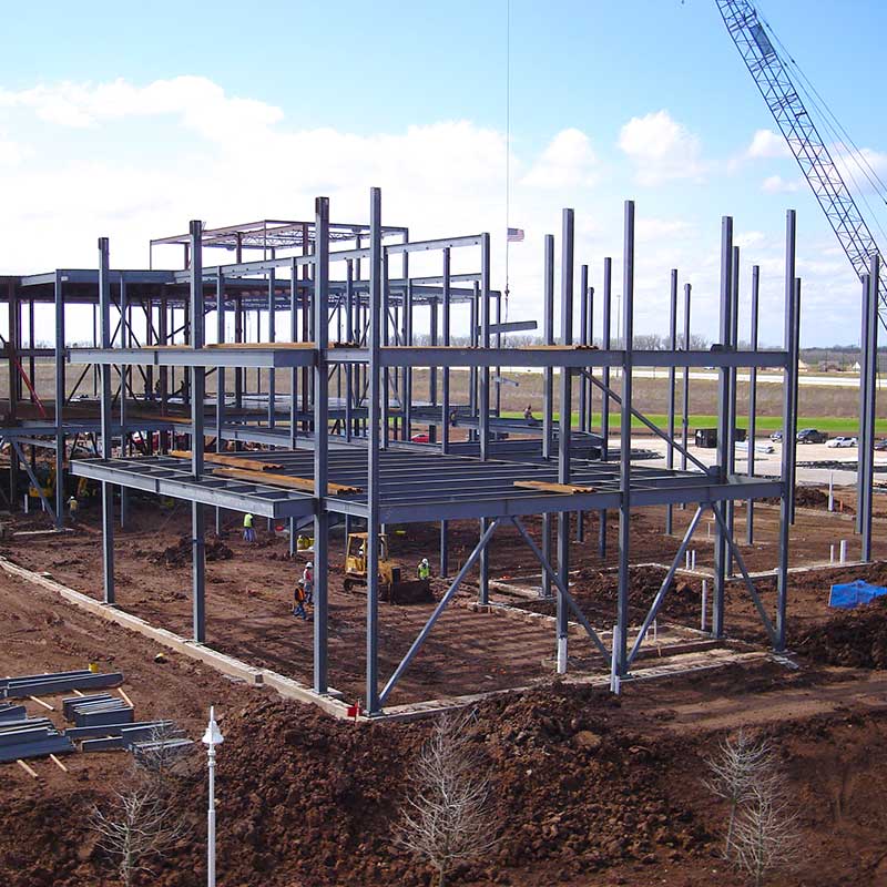 Construction of large building. A construction crew works inside a frame of girders.