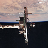 Wake Shield in orbit on shuttle arm over Earth dayside.