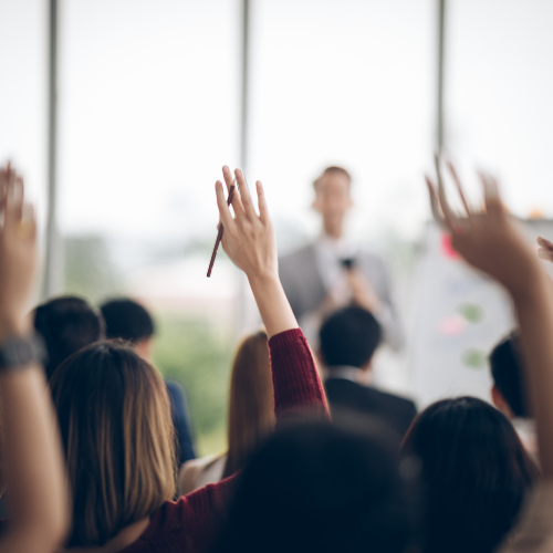 Workshop where attendees have raised hands showing engagement and participation in workshop. 