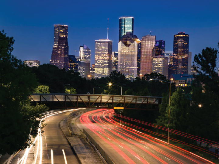 The downtown Houston skyline in the distance with a time lapse of traffic in the foreground